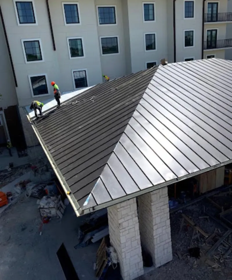 Crew installing standing seam metal roof panels on a commercial project in Hammonton